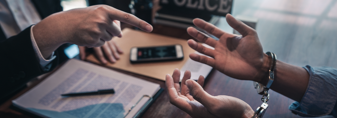 Police officer interrogating suspect or criminal man with handcuffs