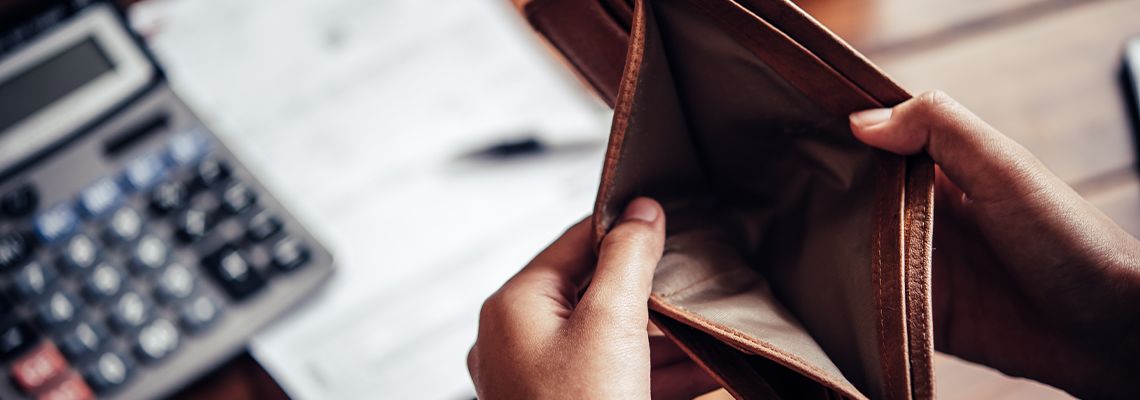 Man with unpaid bills and empty wallet in hand