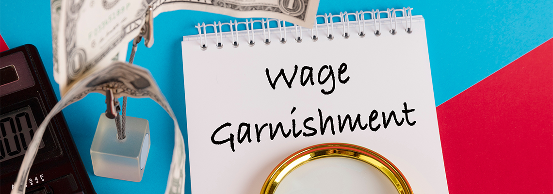 Paper with Wage Garnishment on a table with pen and cash