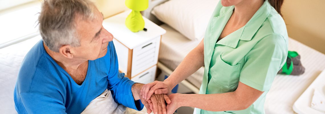 Adult holding hand of a senior in a nursing home