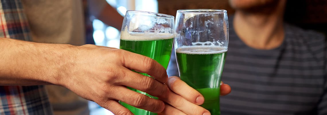 Two people holding glasses filled with green liquid