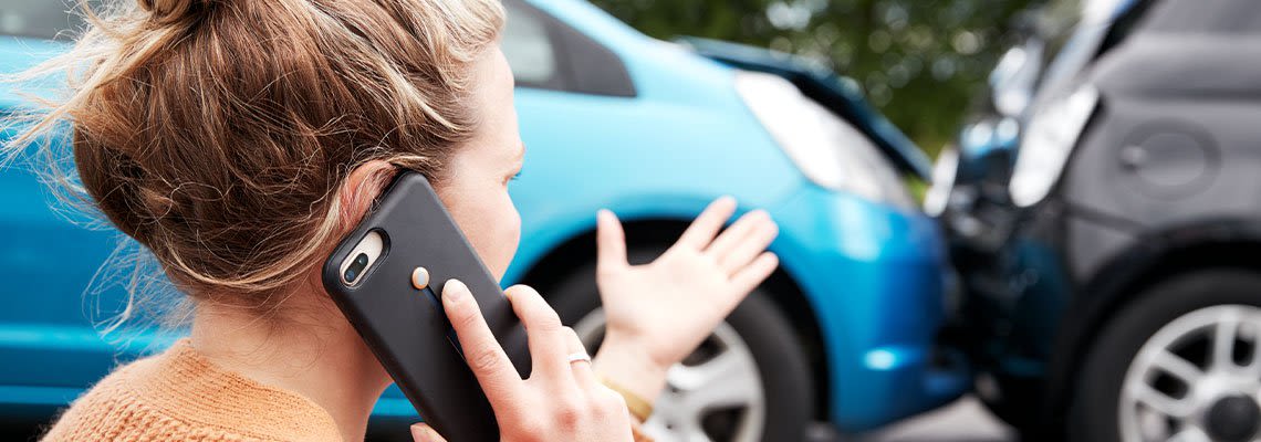 Person on the phone in front of a car accident