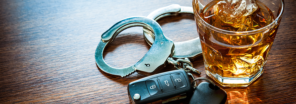 Whiskey, key and handcuff on table