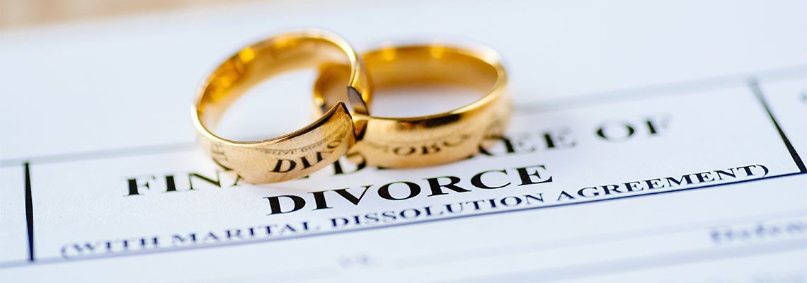 Two broken golden wedding rings and divorce decree document