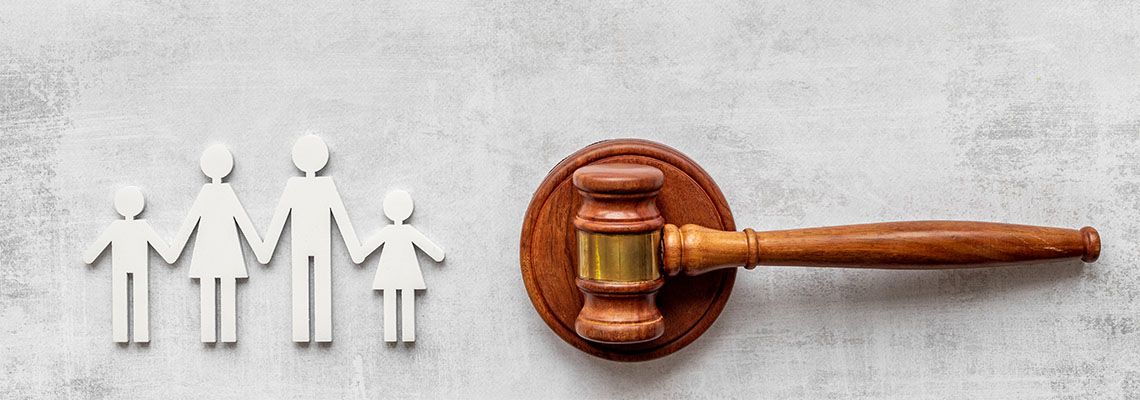 Family figures made out of paper next to judge gavel