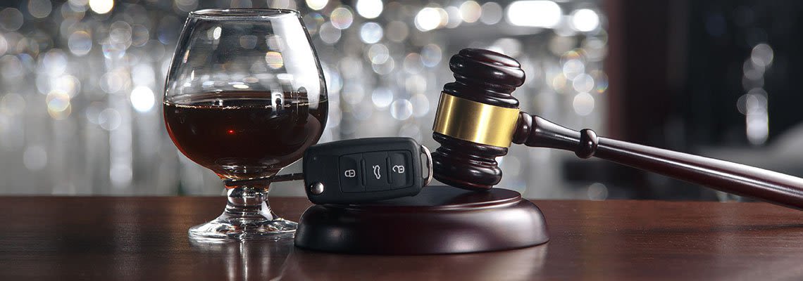 Glass of liquor next to keys and gavel on a bar