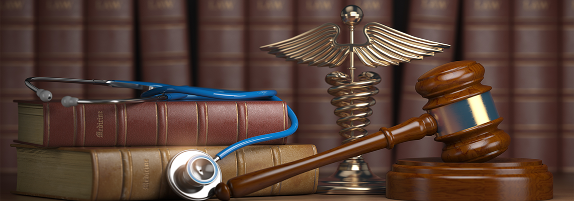 Gavel, stethoscope and caduceus sign on books background.