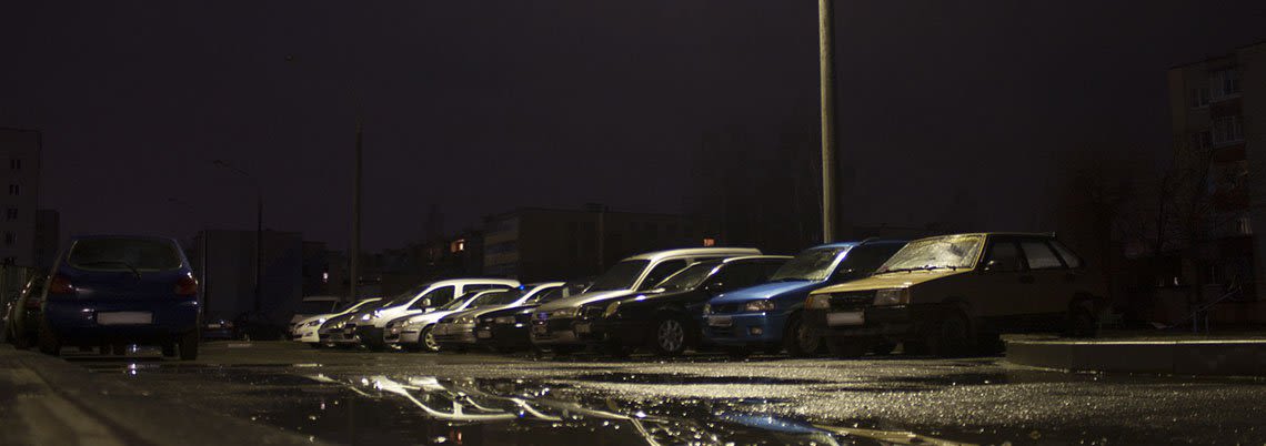 Dark parking lot lighting up a row of old cars