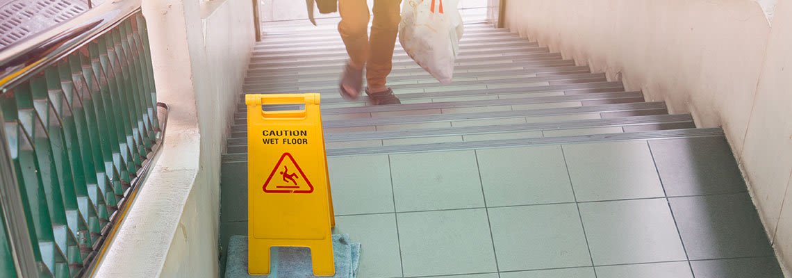 Caution wet floor sign on stairs with a man going up the stairs