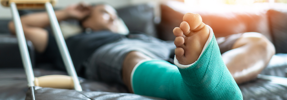 Man lying on a bed with a cast on his leg