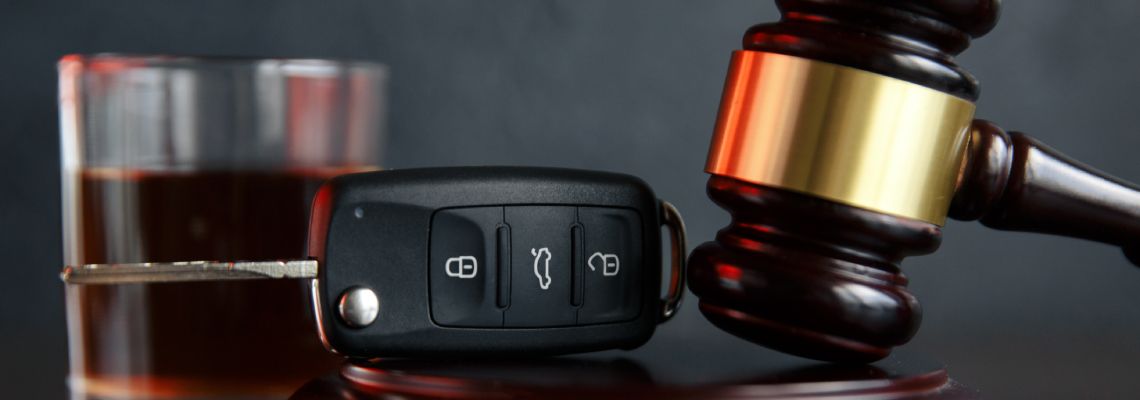 Glass of alcohol, car keys and gavel in table