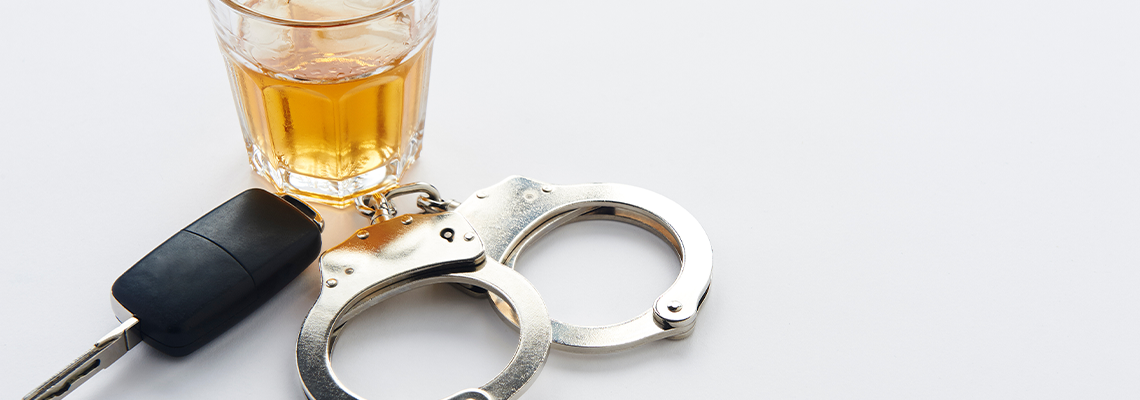 Handcuffs, keys and glass of alcohol on ice with copy space