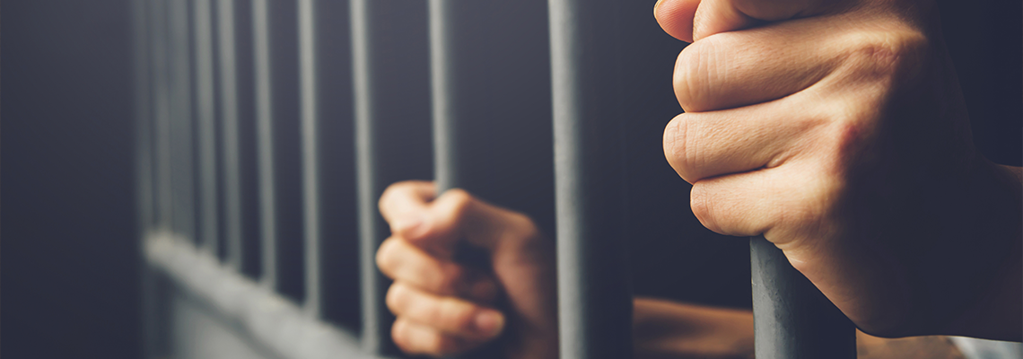 Person behind steel bars gripping them