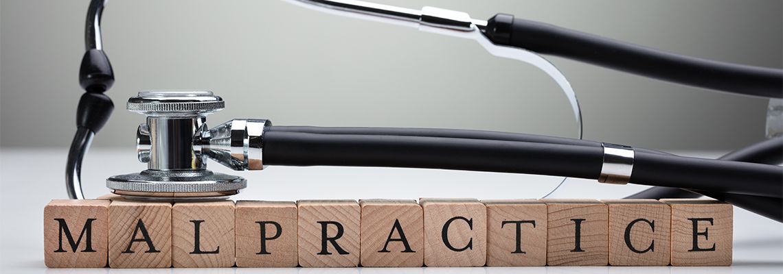 Stethoscope Over Malpractice Wooden Block