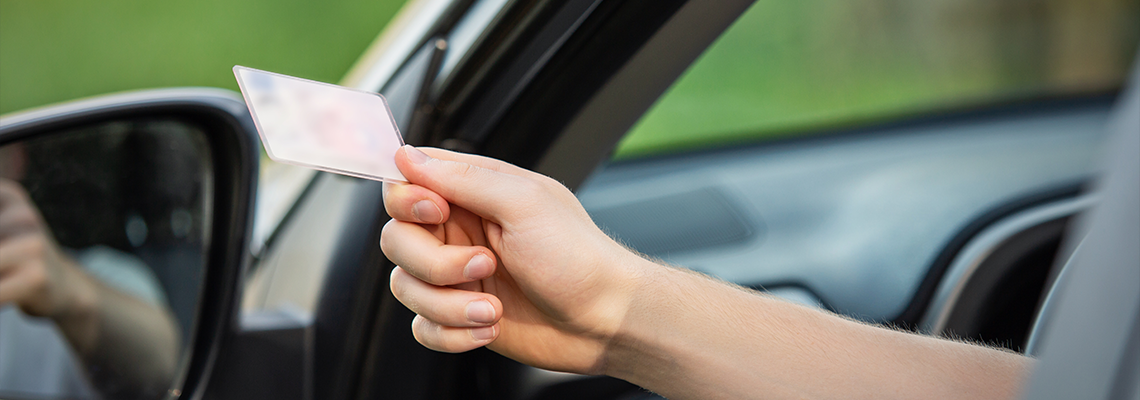 Close up person hand out of the car window holding the driver license