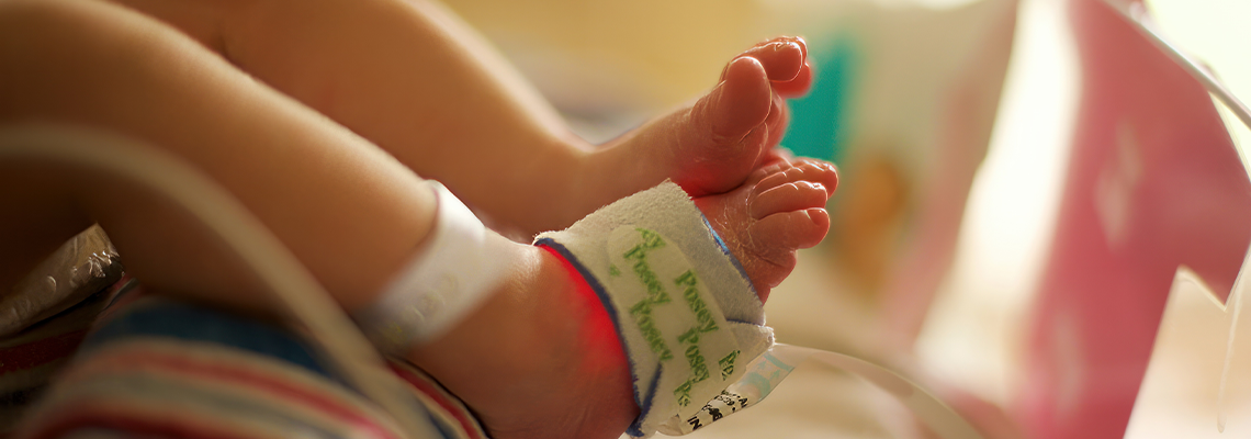 Newborn baby feet closeup in hospital NICU with oxygen monitor