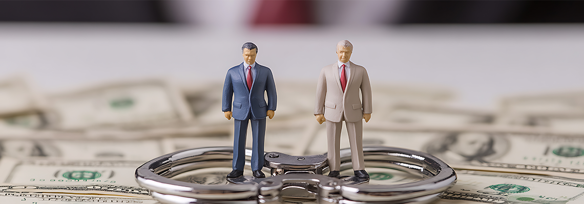 Two figurines in suits stand on handcuffs amidst scattered banknotes