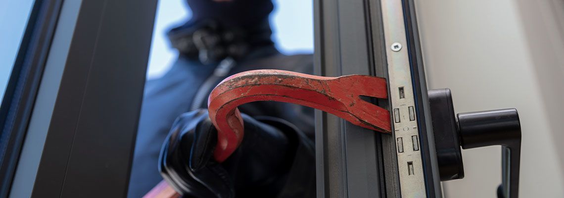 Burglar using crowbar to break into house
