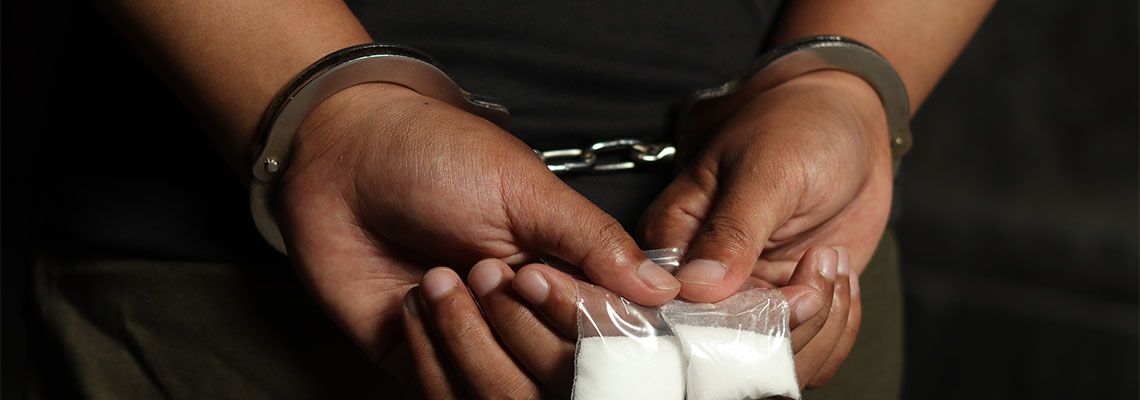 Handcuffed man holding drug in hand