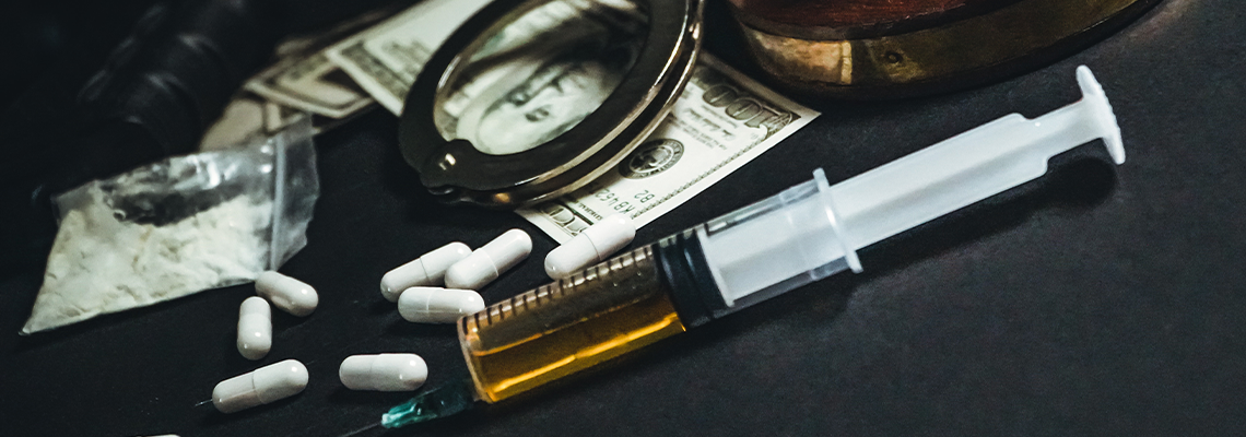 Different types of drugs and handcuff on table