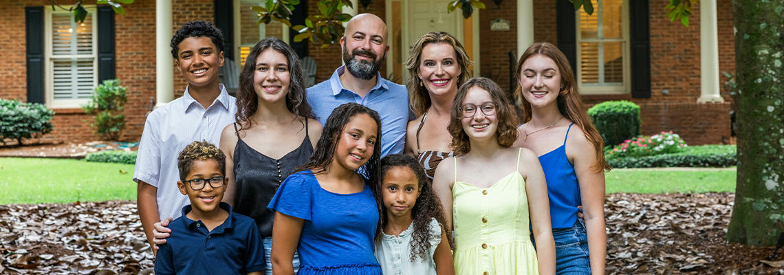 A large and blended and mixed happy family standing in front of their home