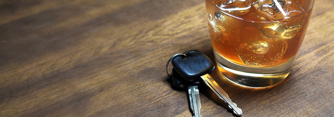 Glass of alcohol sitting next to keys