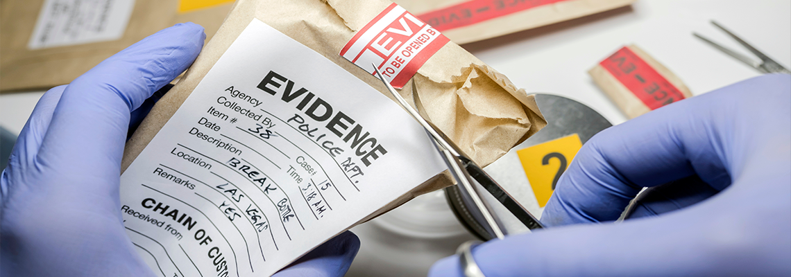 Scientific police opens with scissors a bag of evidence of a crime in scientific laboratory