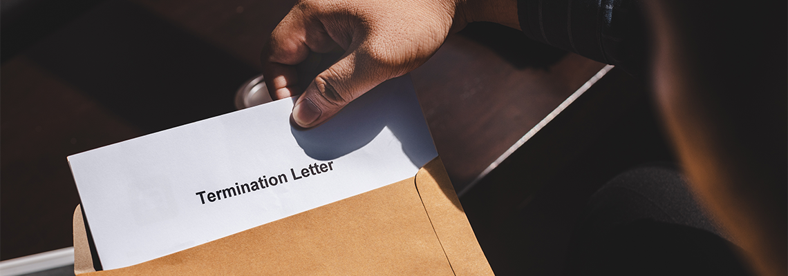 Person Pulling Termination Letter Out of Envelope