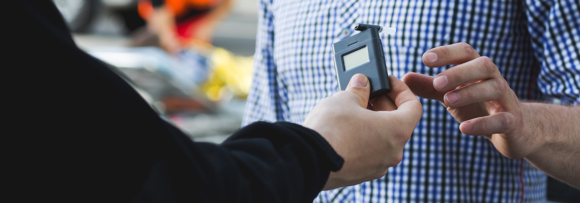 Policeman Giving a Breathalyzer to A Driver