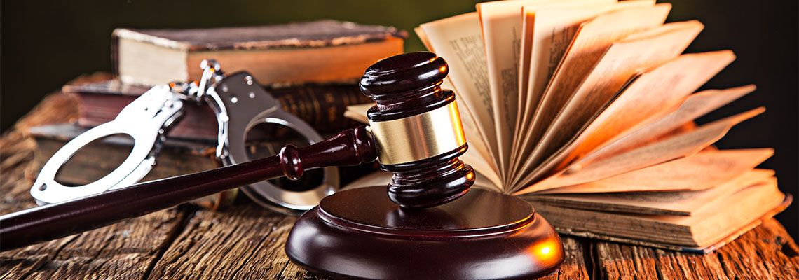 Wooden gavel, handcuff and books on wooden table