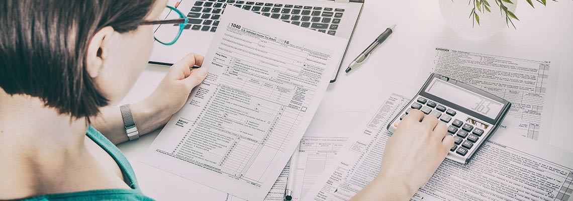 Woman looking at debt papers while working on a calculator