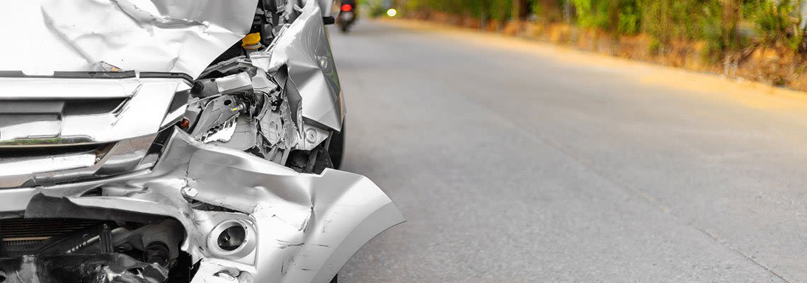 Silver sedan with the front bumper smashed in from an accident