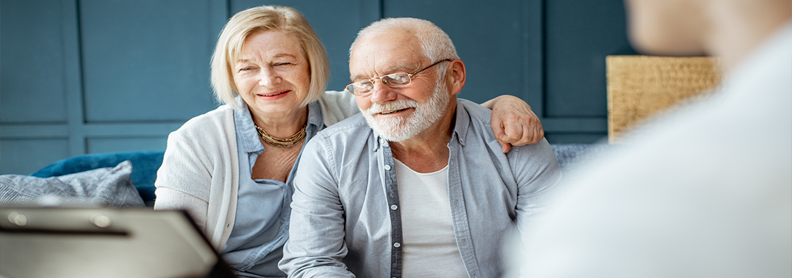 Two older people smiling and sitting across from someone