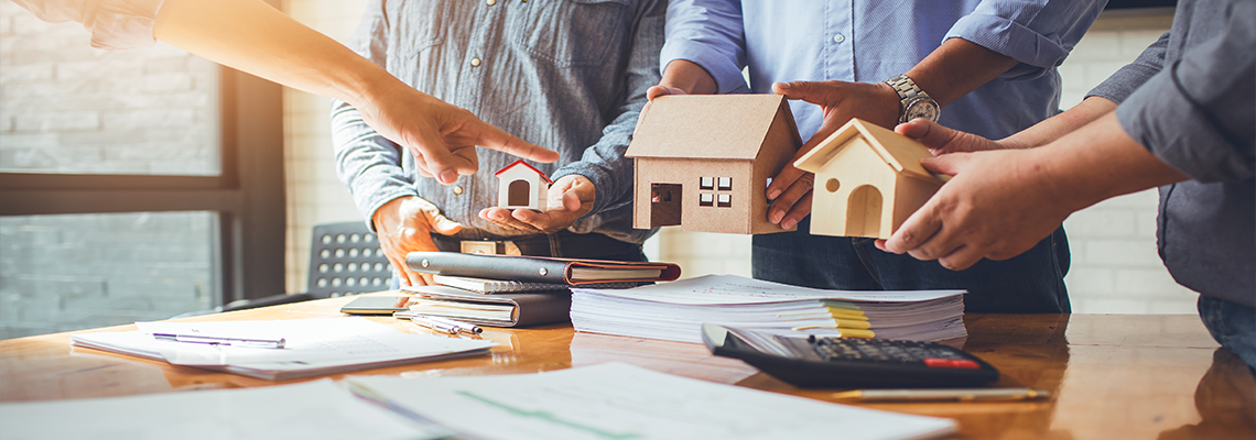 Men putting toy houses on paperwork