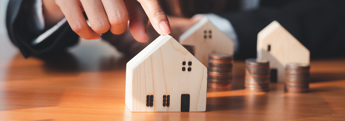 Model houses and stacks of coins on a desk