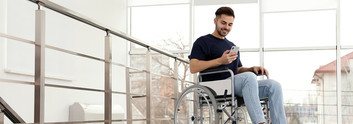 A man in a wheelchair uses his cell phone