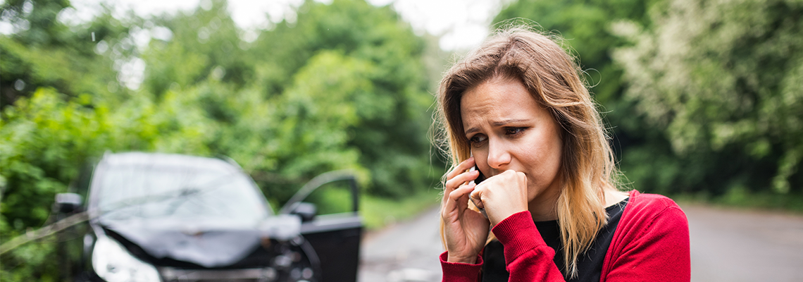 A woman talks on the phone after a serious car accident