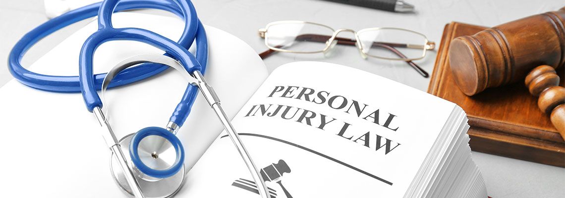 Book with words PERSONAL INJURY LAW and stethoscope on table