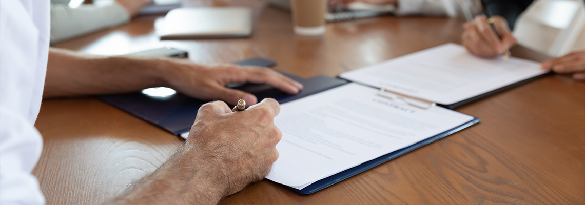 Two business partners signing agreement documentations after negotiations.