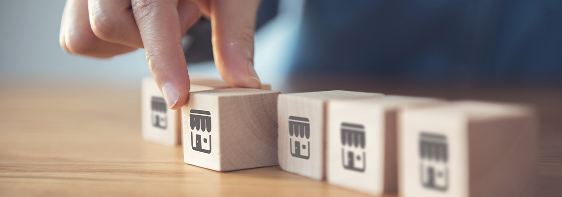 A hand picks up a small wooden block with Franchise Icon
