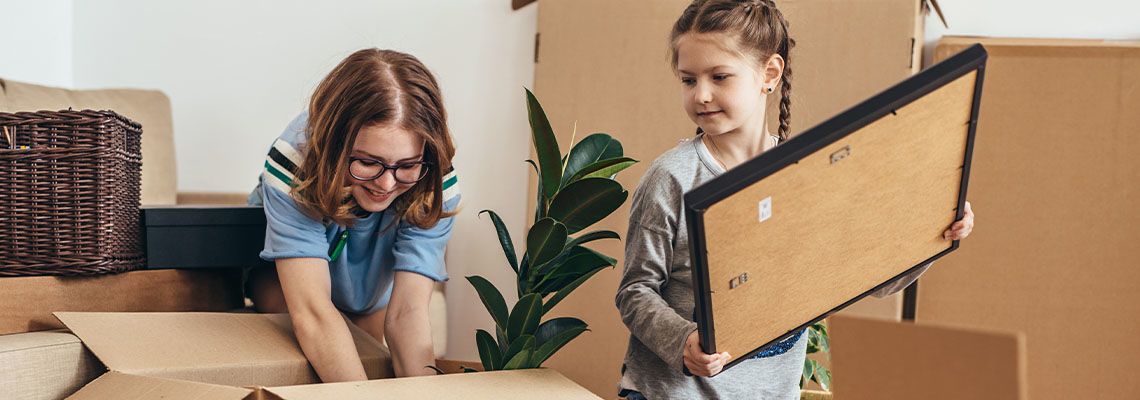 Little girls unpacking cardboard boxes at new home