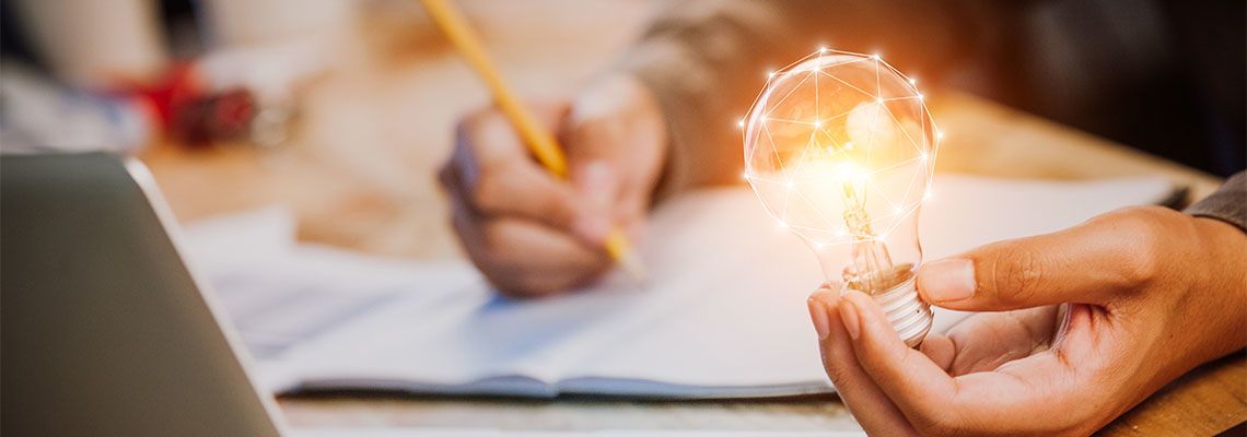 Man holding light bulb in hand and noting down ideas