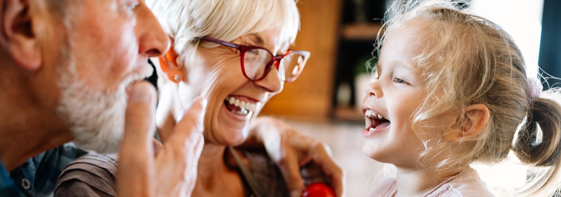 Happy grandparents playing with their little cute granddaughter