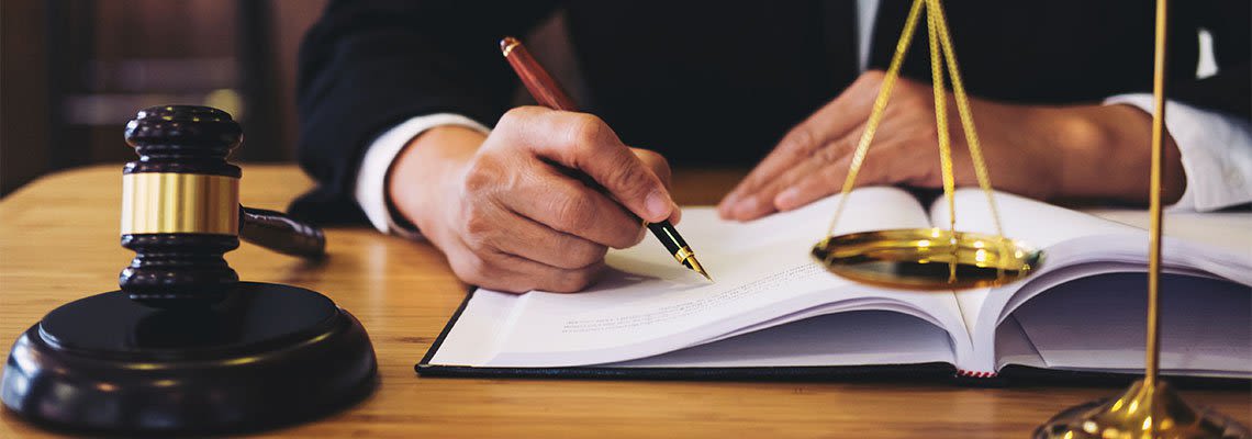 Person writing at desk with gavel and scales