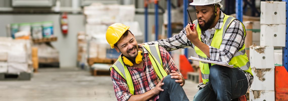Supervisor helping injured worker in factory