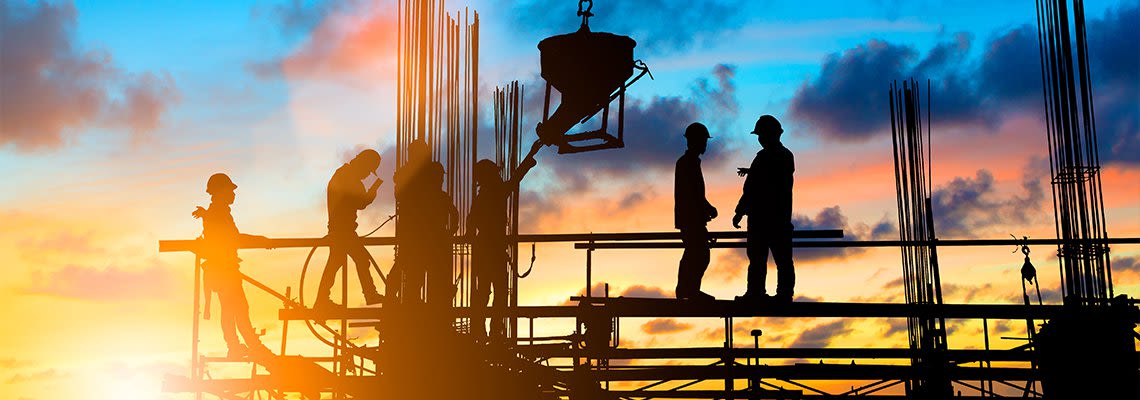 Construction workers standing on metal structure at dusk