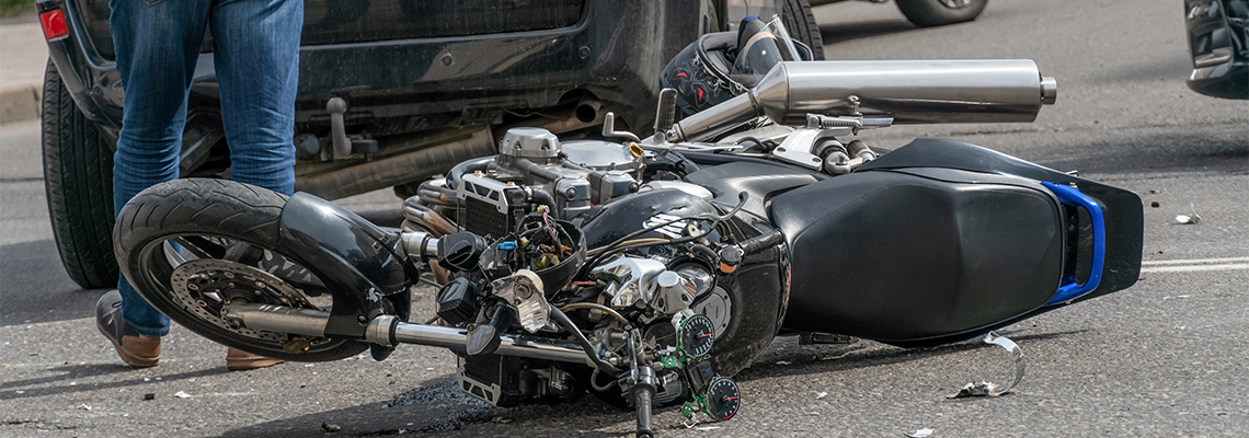 Broken motorcycle closeup beside the car