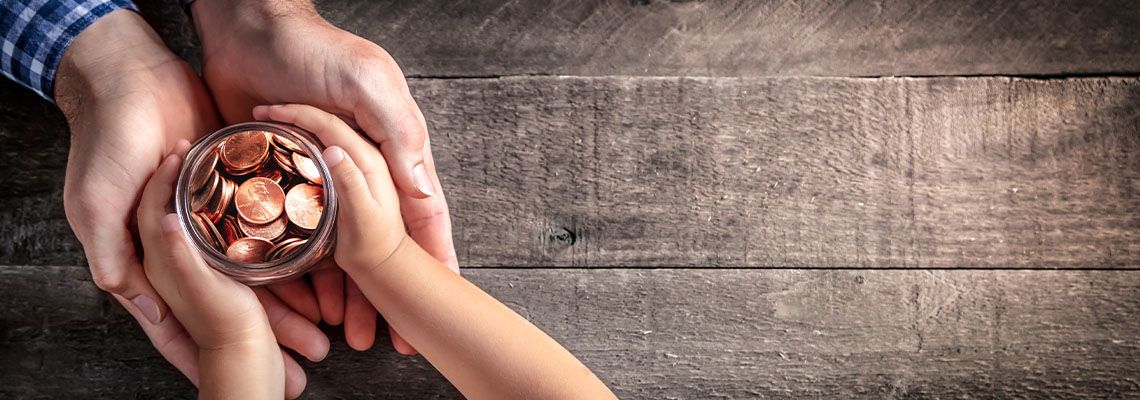 Hands of Father Giving Jar of Coins To Child