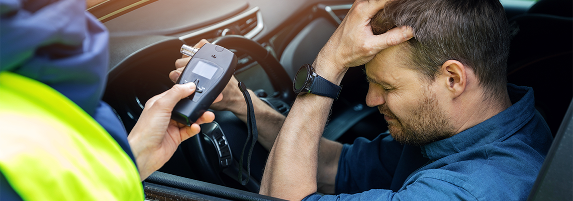 Sad drunk man sitting in the car after police alcohol test with alcometer