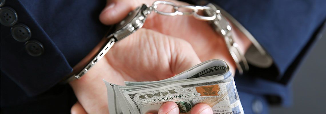 Handcuffed businessman holding money in hand